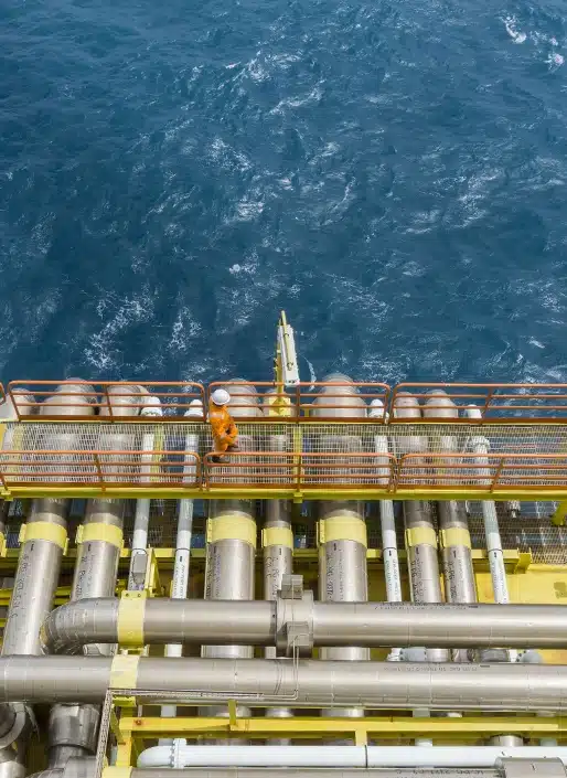 A man walking on bridge in ocean with pipes surrounding him