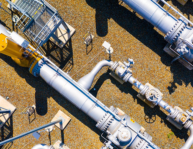 Aerial shot of pipes and tanks, with stairs going to them. The ground is orangish brown