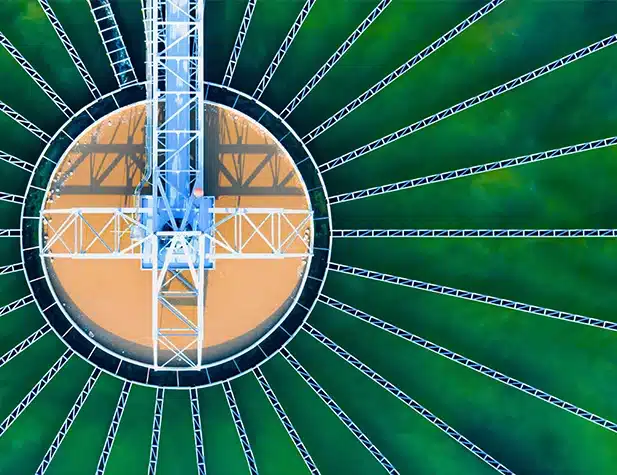Aerial view of green water with a treatment plant in the middle