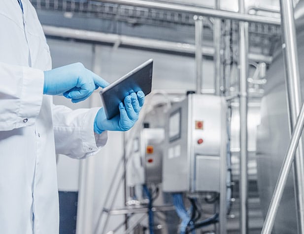 Person in lab with lab coat and gloves on, holding a tablet and clicking something