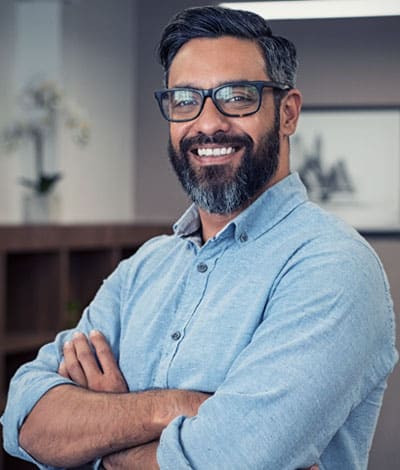 Portrait professionnel d'un dirigeant d'entreprise souriant, les bras croisés, dans un bureau.
