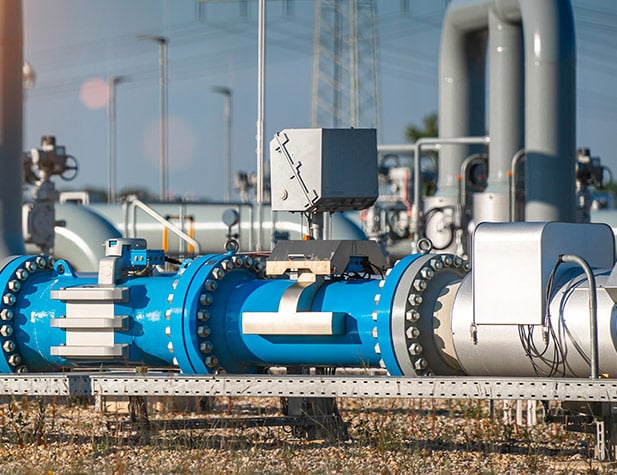 Blue pipeline infrastructure in an industrial plant setting, with metallic valves and control units.