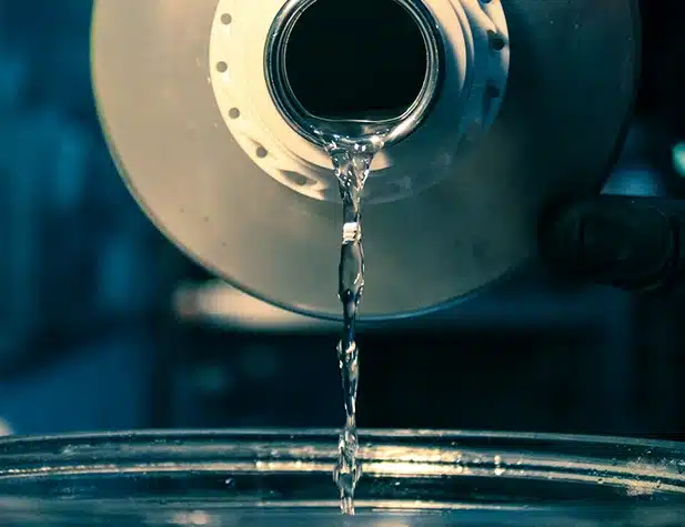 Un liquide transparent s'écoule d'un objet cylindrique dans un bol
