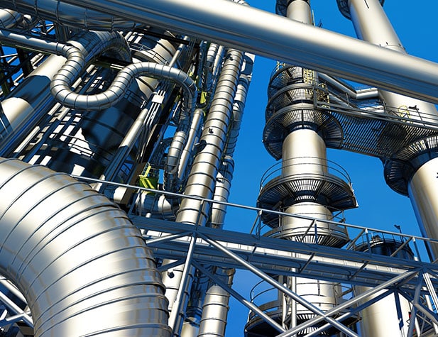 Upward view of tall metal pipes, some are bending, two have stairs going up and connecting them, with the blue sky in the background.